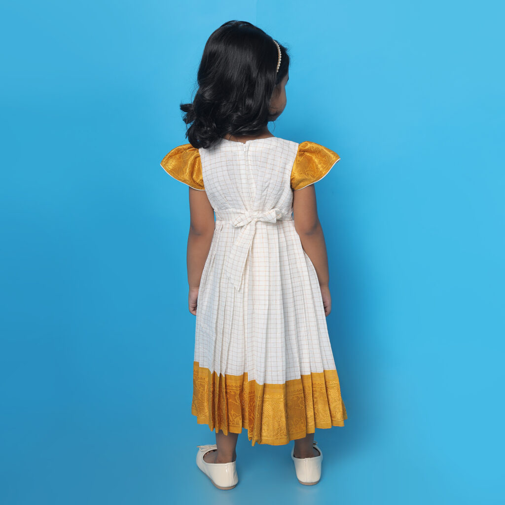 Styled flat lay of Amora mustard and white patterned kids frock