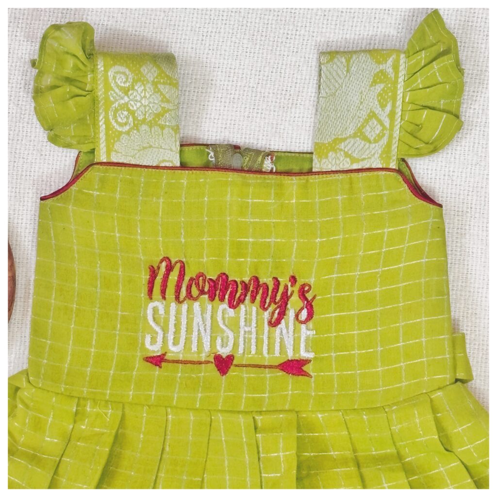 Styled flat lay of sky blue Sungudi kids frock with embroidered bodice and pleated skirt