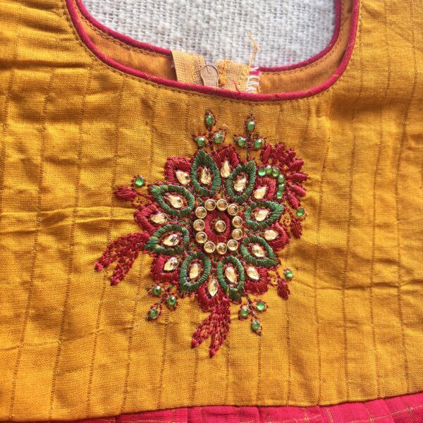 Decorative embroidery detail on mustard yellow bodice of kids festive frock