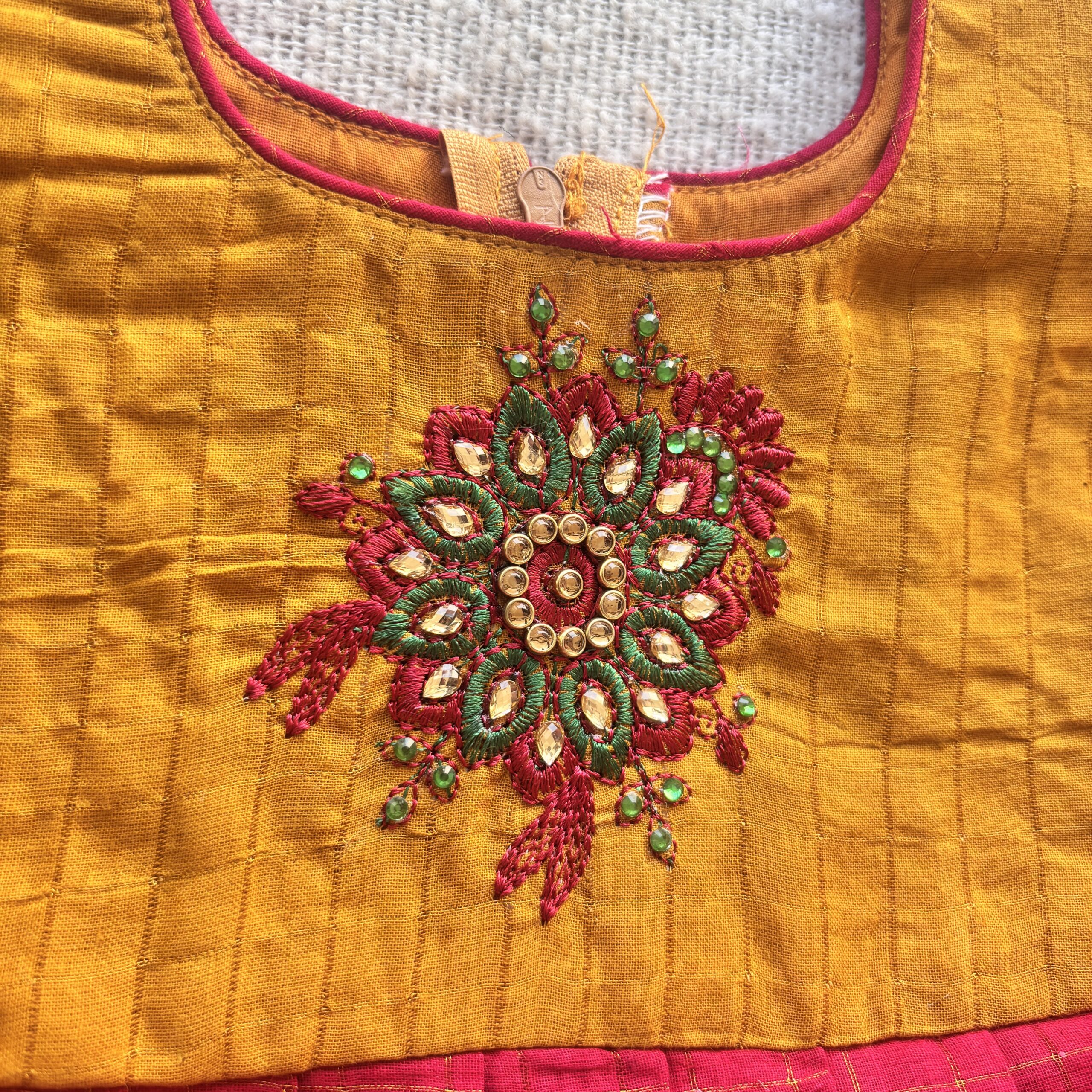 Decorative embroidery detail on mustard yellow bodice of kids festive frock