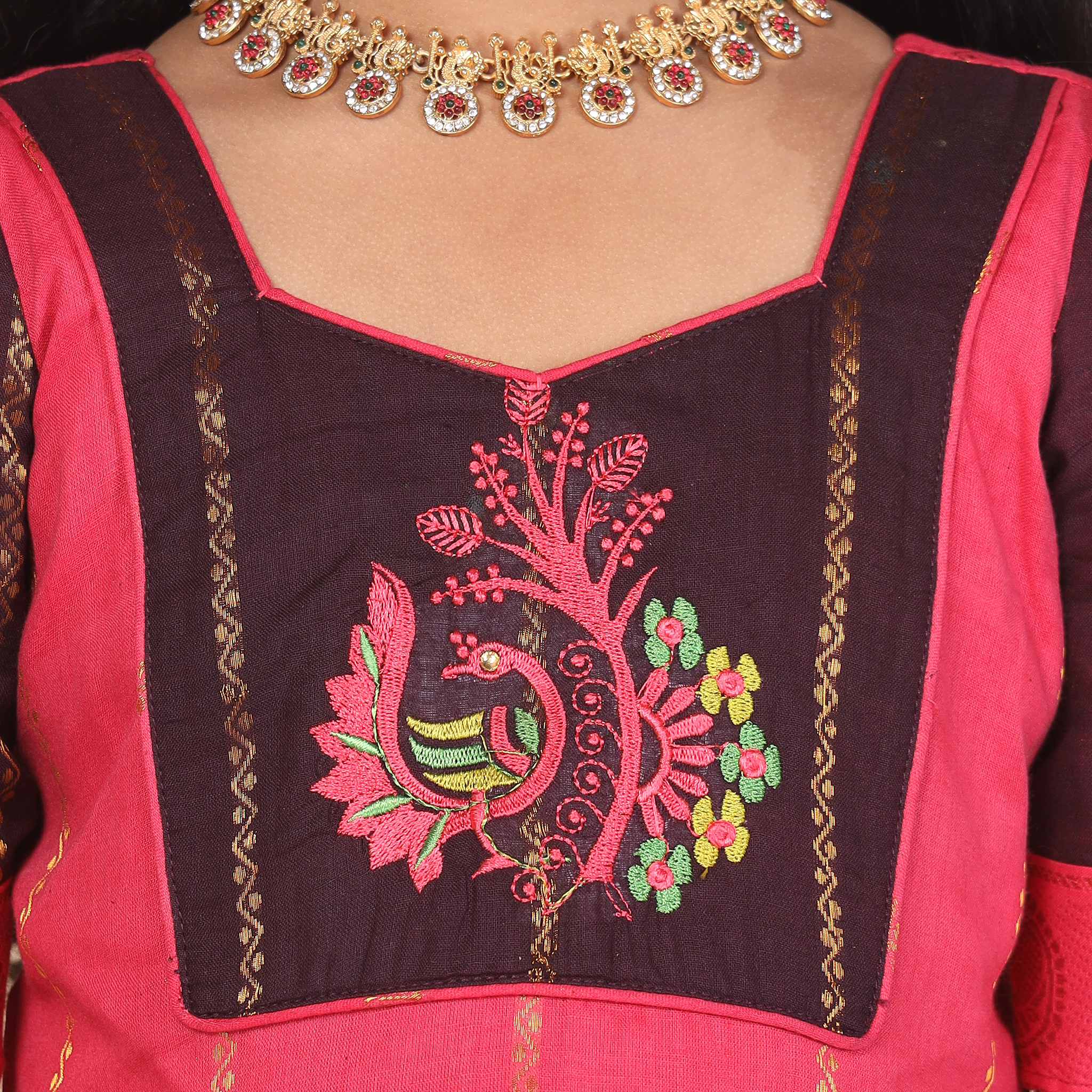 Close up traditional pattern detail on deep brown and pink ethnic long gown