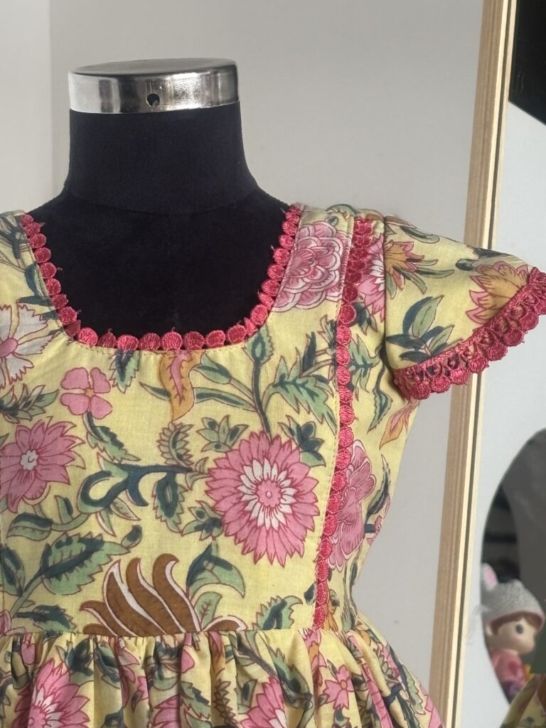 Front view of yellow floral cotton girls frock with gathered skirt