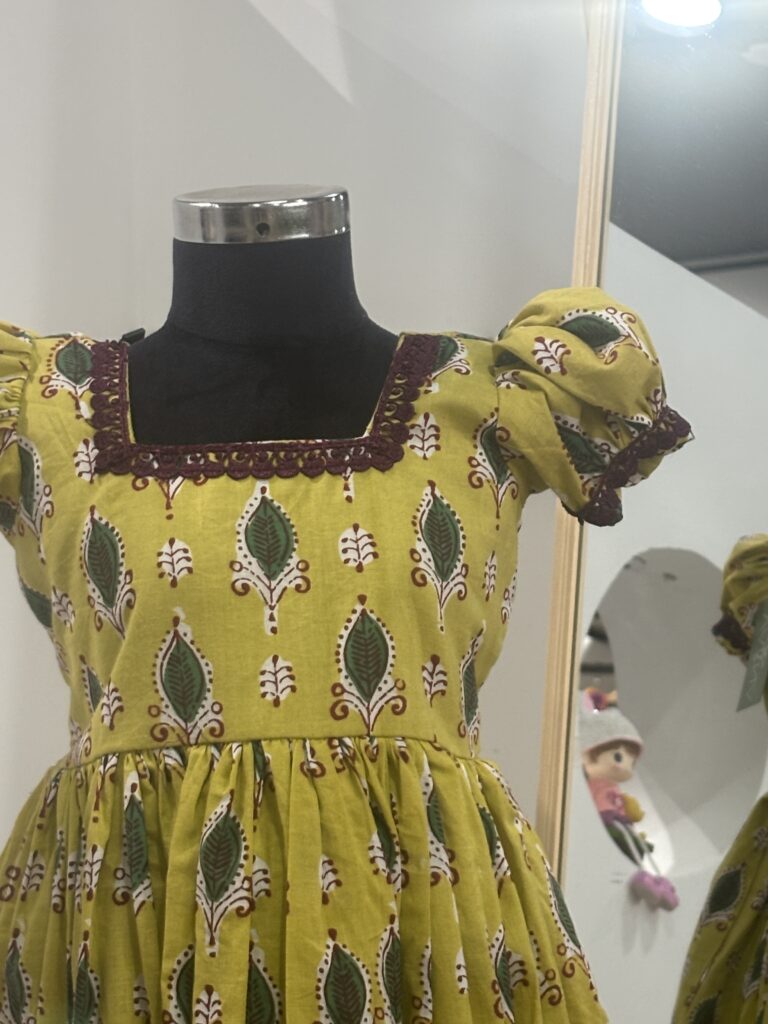 Front view of yellow cotton girls frock with gathered skirt
